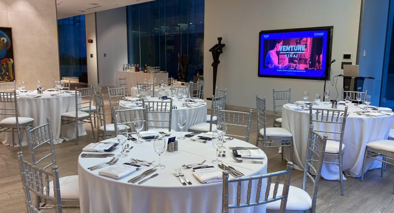 event dinner tables and screen that reads venture siani